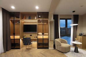 Ein modernes Hotelzimmer mit einem großen Bett, einer Sitzecke, einem Fernseher und Blick auf die Stadt.