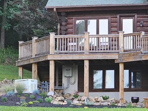 Eine zweistöckige Blockhütte mit Balkon, Sitzgelegenheiten im Freien und einem Generator.