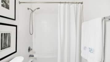 Un baño con bañera, ducha, inodoro y cuadros en la pared.