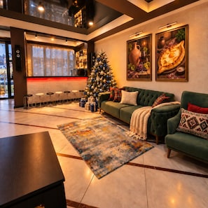 A modern living room with a green sofa, a Christmas tree, and a bar area with stools.
