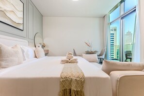 A hotel room with a large bed, a small table with chairs, and a view of the city through the window. - HAVN - High floor Studio, Burj Khalifa View (Dubai)