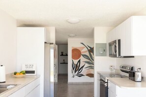 A modern kitchen with white cabinetry, a stainless steel refrigerator, and a built-in oven. - Modern Dorado Beach House with Pool (dorado)
