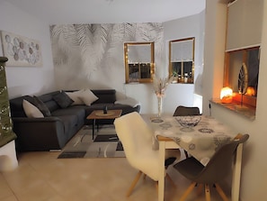 A living room with a sofa, coffee table, and dining area with chairs and a table.
