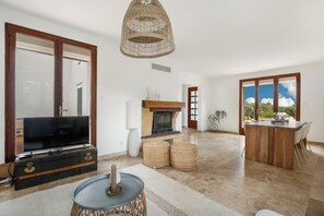 Amplia sala de estar con televisor, chimenea y comedor con vistas.