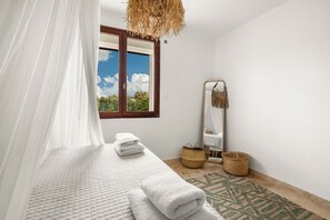 Un dormitorio con cama, ventana, espejo y lámpara colgante.