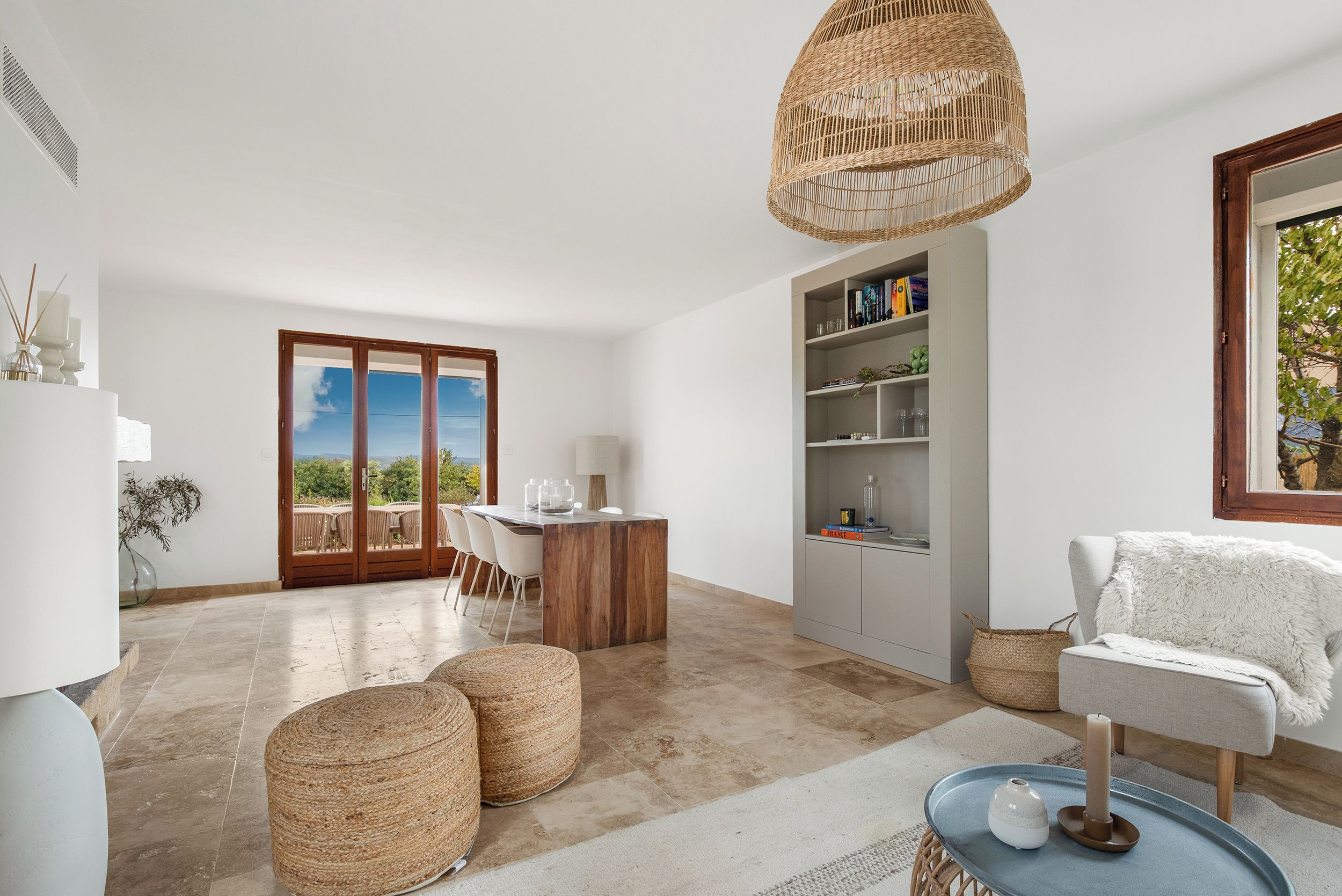 A modern interior with a dining area, a bookshelf, and a view through a glass door.
