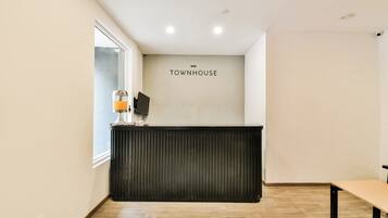 Uma receção com uma placa 'TOWNHOUSE', uma janela e chão de madeira.