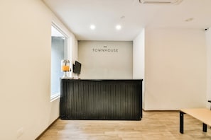 Una recepción con un letrero que dice 'TOWNHOUSE', una ventana y un piso de madera.