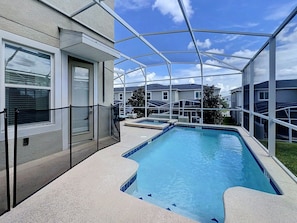 A swimming pool with a glass enclosure, surrounded by a building with windows and a door. - Sunshine Retreat: Private Pool and Spa! (Davenport)