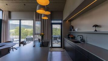 Een moderne keuken met een groot eiland, hanglampen en uitzicht op de omgeving.
