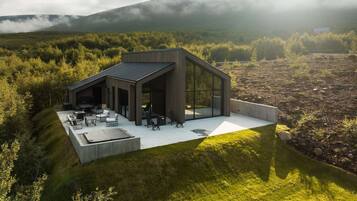 Una casa moderna con techo plano, ventanas amplias y un patio con mobiliario exterior.