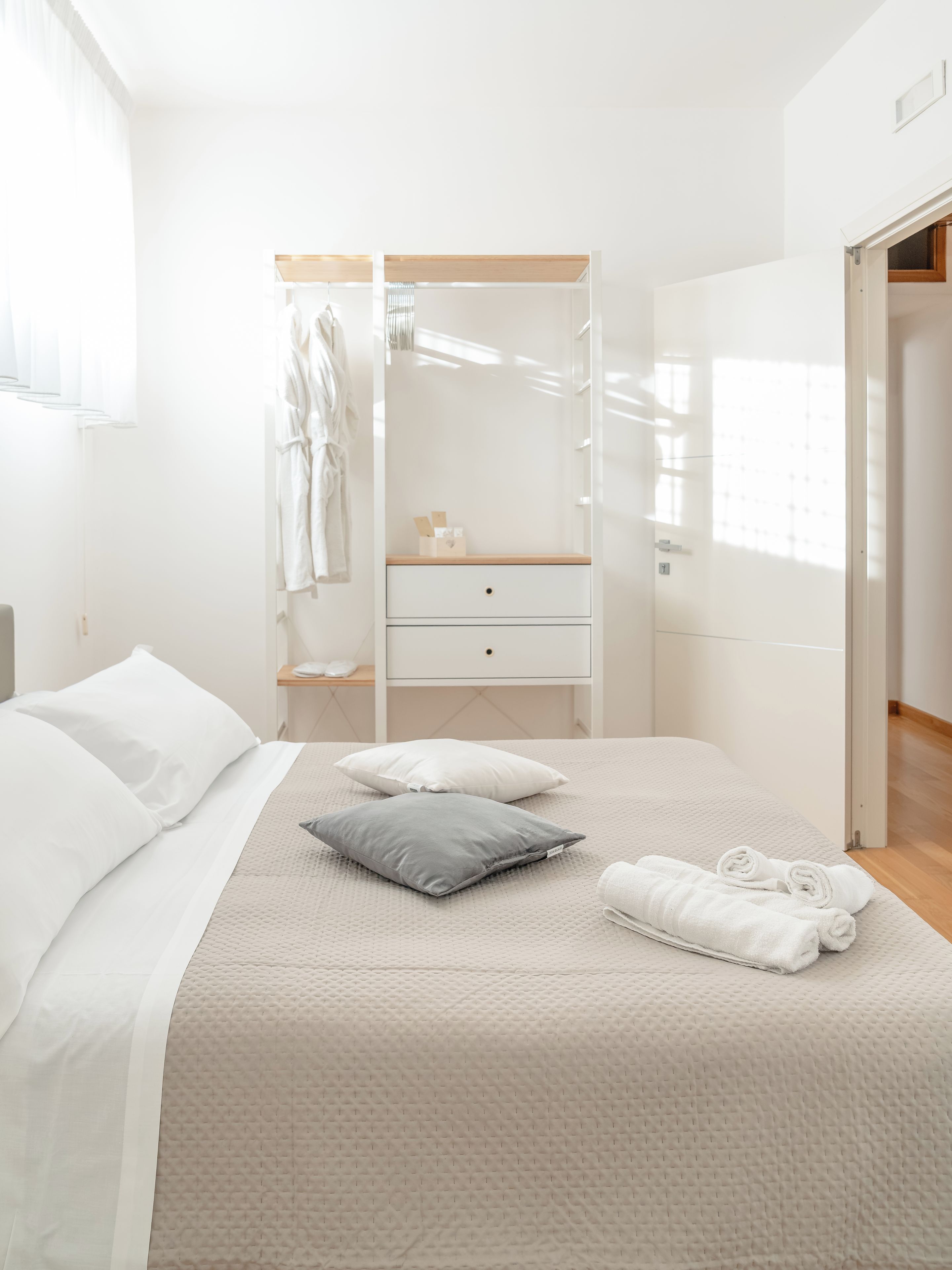 Habitación de hotel con una cama, un armario, una mesita de noche y una puerta que da a otra habitación.