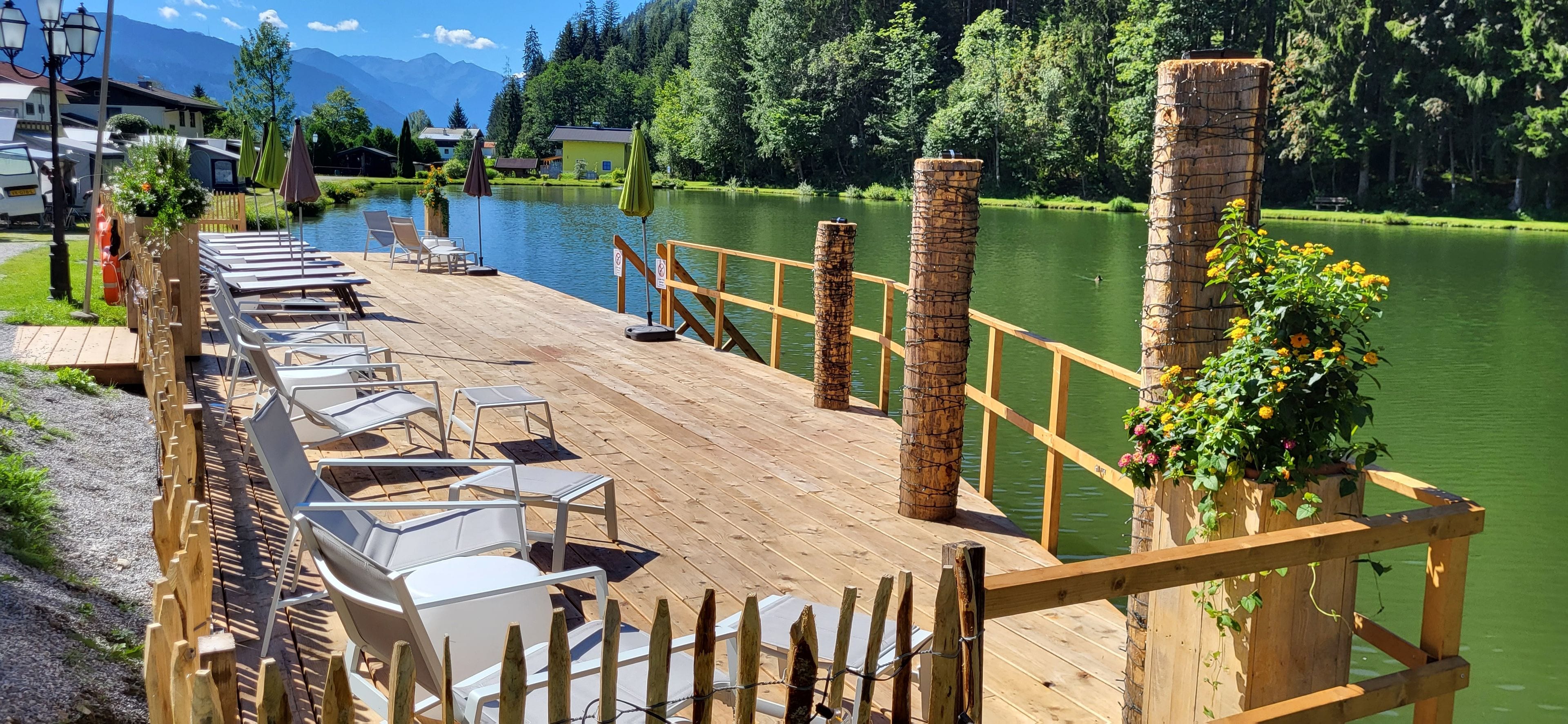 Un pontile di legno con poltrone relax e vista su un lago.