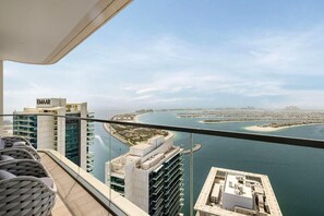 A high-rise building with a view of a coastal cityscape, including a marina and a large body of water. - Luxury 3BR Palm Views Emaar Beachfront (Dubai)