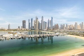 A marina with boats and a city skyline in the background. - Luxury 3BR Palm Views Emaar Beachfront (Dubai)