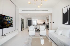 A modern living room with a flat-screen TV, a sofa, two armchairs, and a coffee table. - Luxury 3BR Palm Views Emaar Beachfront (Dubai)