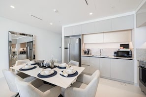 A modern kitchen with a dining area, featuring a large island, built-in appliances, and a clean, minimalist design. - Luxury 3BR Palm Views Emaar Beachfront (Dubai)