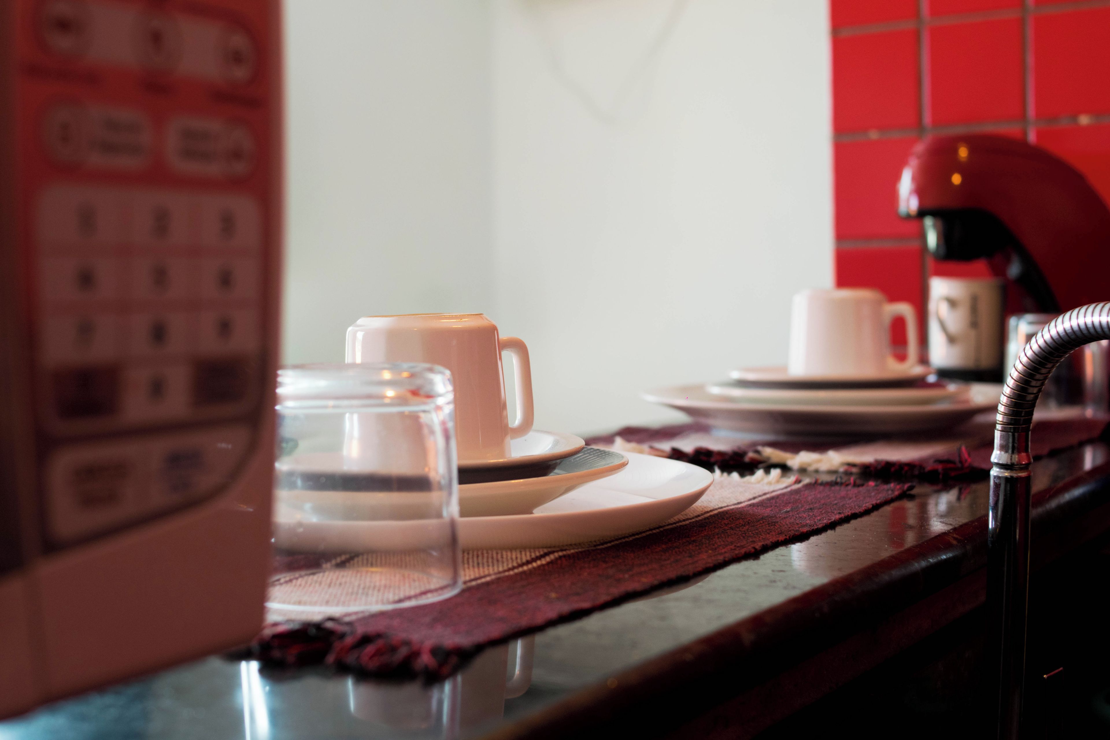 A kitchen counter with a coffee cup, a glass jar, and a tea set.
