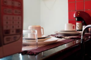 En köksbänk med en kaffekopp, en glasburk och ett teservis.