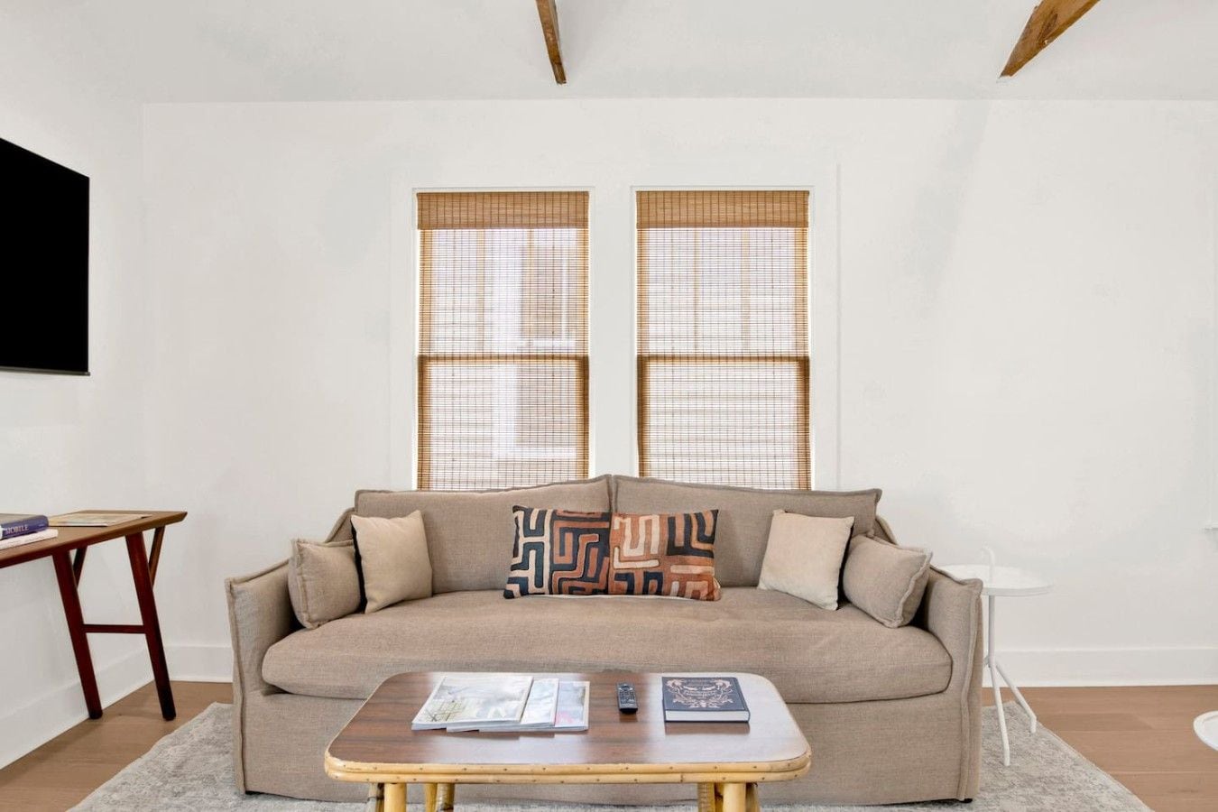 Ein Wohnzimmer mit einer Couch, einem Couchtisch und zwei Fenstern mit Jalousien.