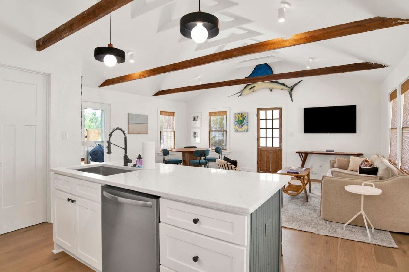 A spacious kitchen with a large island, wooden beams on the ceiling, and a dining area with a round table and chairs.