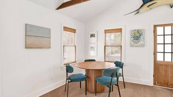 A dining area with a round wooden table, four chairs, and a large fish mounted on the wall.
