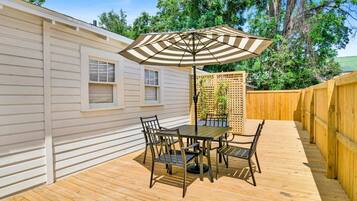 A wooden deck with a table and chairs, an umbrella, and a wooden fence.