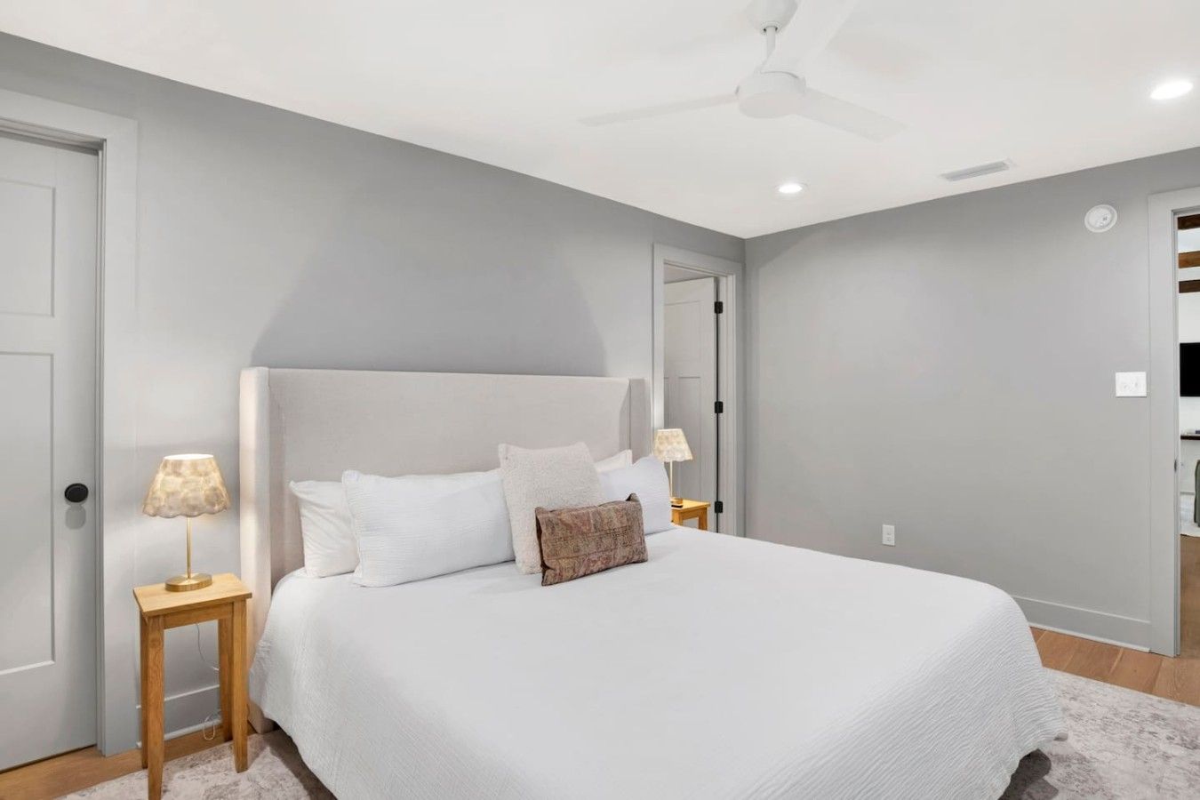 A bedroom with a bed, two bedside tables, a ceiling fan, and a door.