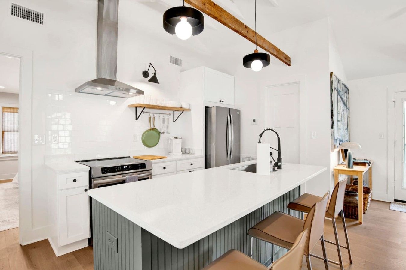 Una cucina moderna con una grande isola, elettrodomestici in acciaio inossidabile e luci a sospensione.