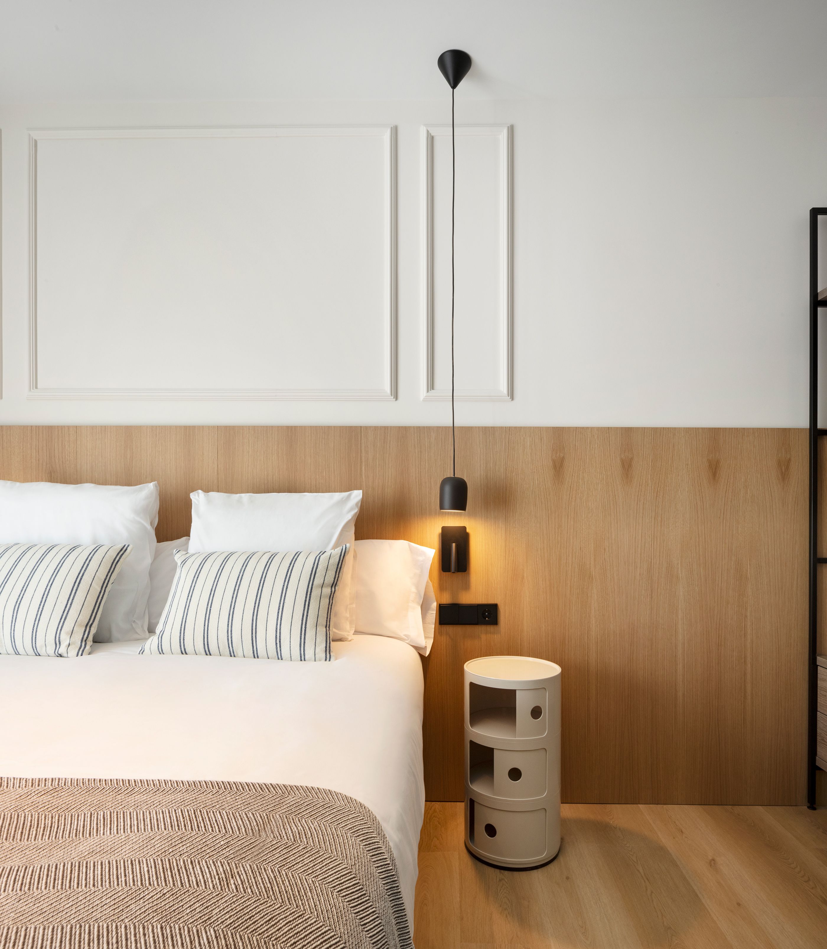Un dormitorio moderno con cama, mesitas de noche y una lámpara de pared.