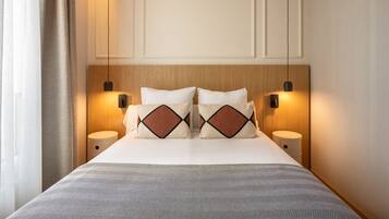 Een hotelkamer met een bed, twee nachtkastjes, een hoofdeinde en wandlampen.