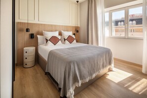 Una cama bien hecha con una manta a rayas, una lámpara de noche y una mesita de noche con cajones.