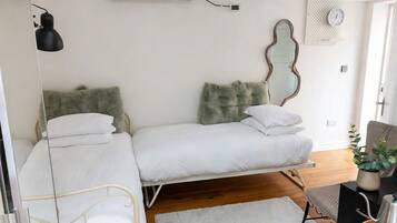 A bedroom with a bed, bedside tables, a mirror, a clock, and a plant.
