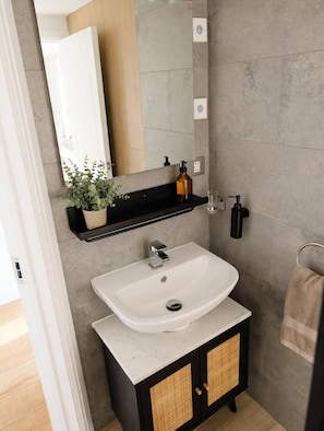A bathroom with a white sink, black cabinet, and a mirror above. - Light-fitted studio, 7 mini walk to Elizabeth line (Slough)