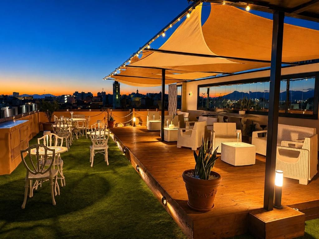 A rooftop terrace with outdoor seating, a view of the cityscape, and a sunset.