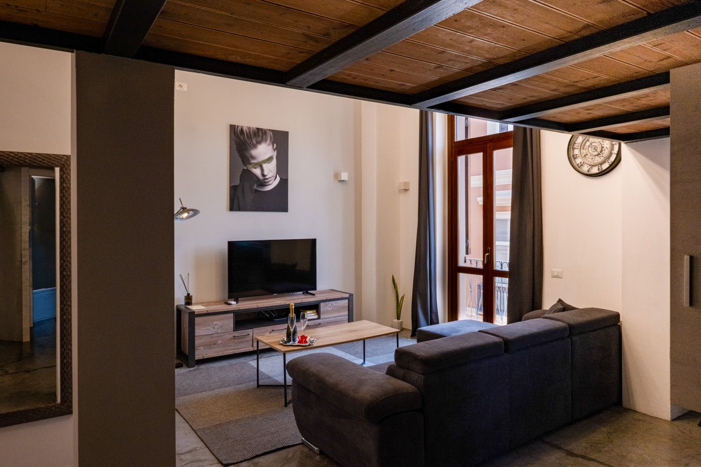 Una sala moderna con un sofá, un televisor y un techo de madera.