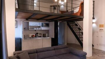 Ein modernes Interieur mit einem grauen Sofa, einer Küchenzeile und einer Treppe.