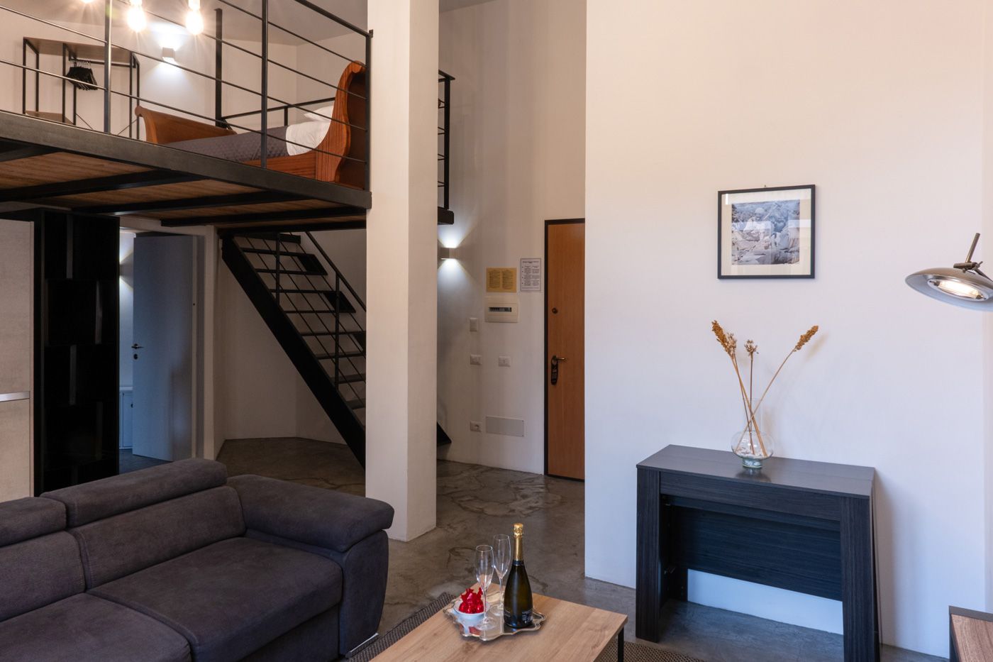 A modern living room with a sofa, a fireplace, a staircase, and a framed picture on the wall.