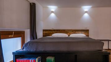 Un lit avec une tête de lit en bois, deux lampes de chevet et une table de chevet avec des livres.