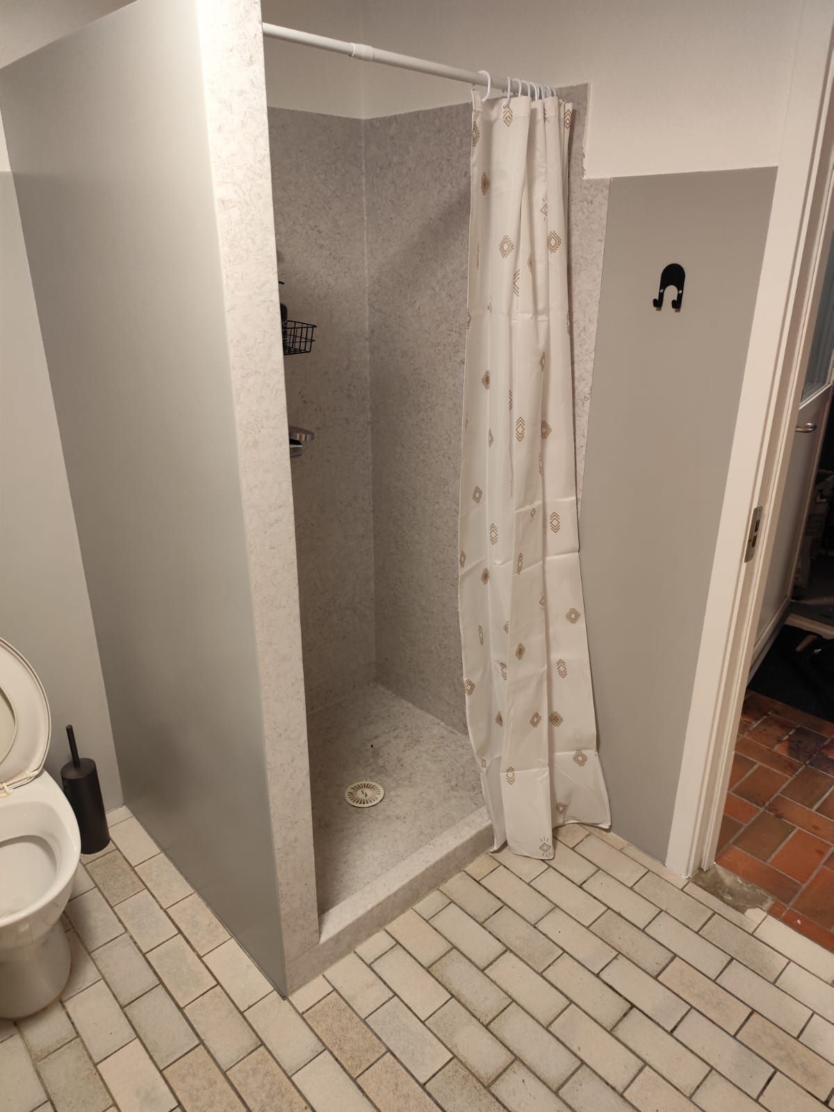 Un baño con ducha, inodoro y barra para toallas.
