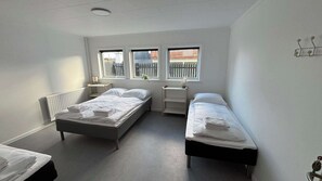 Quarto com duas camas, um radiador e uma janela com persianas.