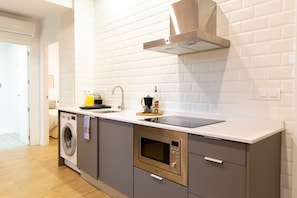 Una cocina moderna con lavadora integrada, microondas y pileta.