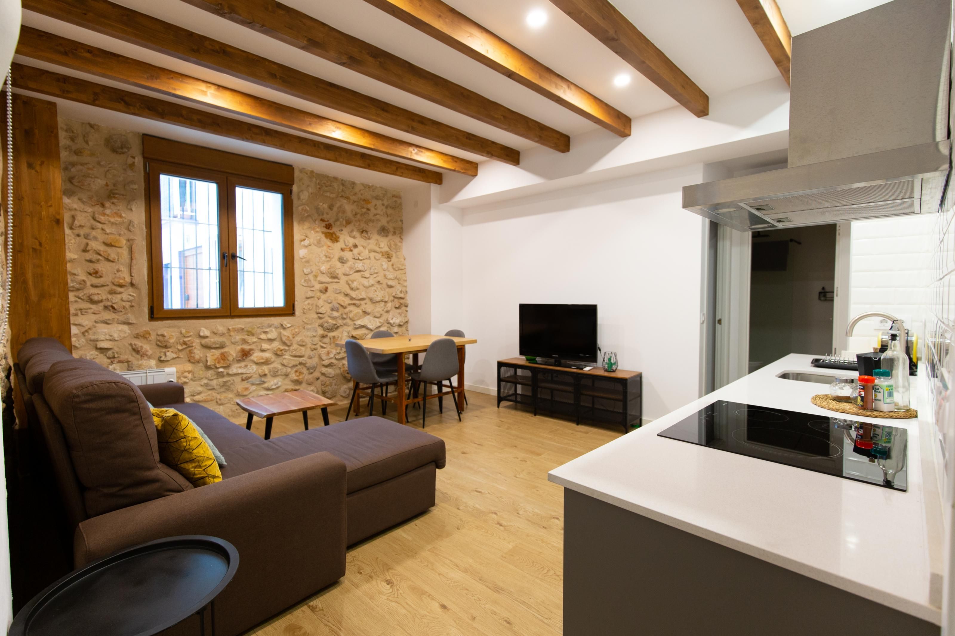 A modern living room with a sofa, a dining table, and a kitchen area with a stove.