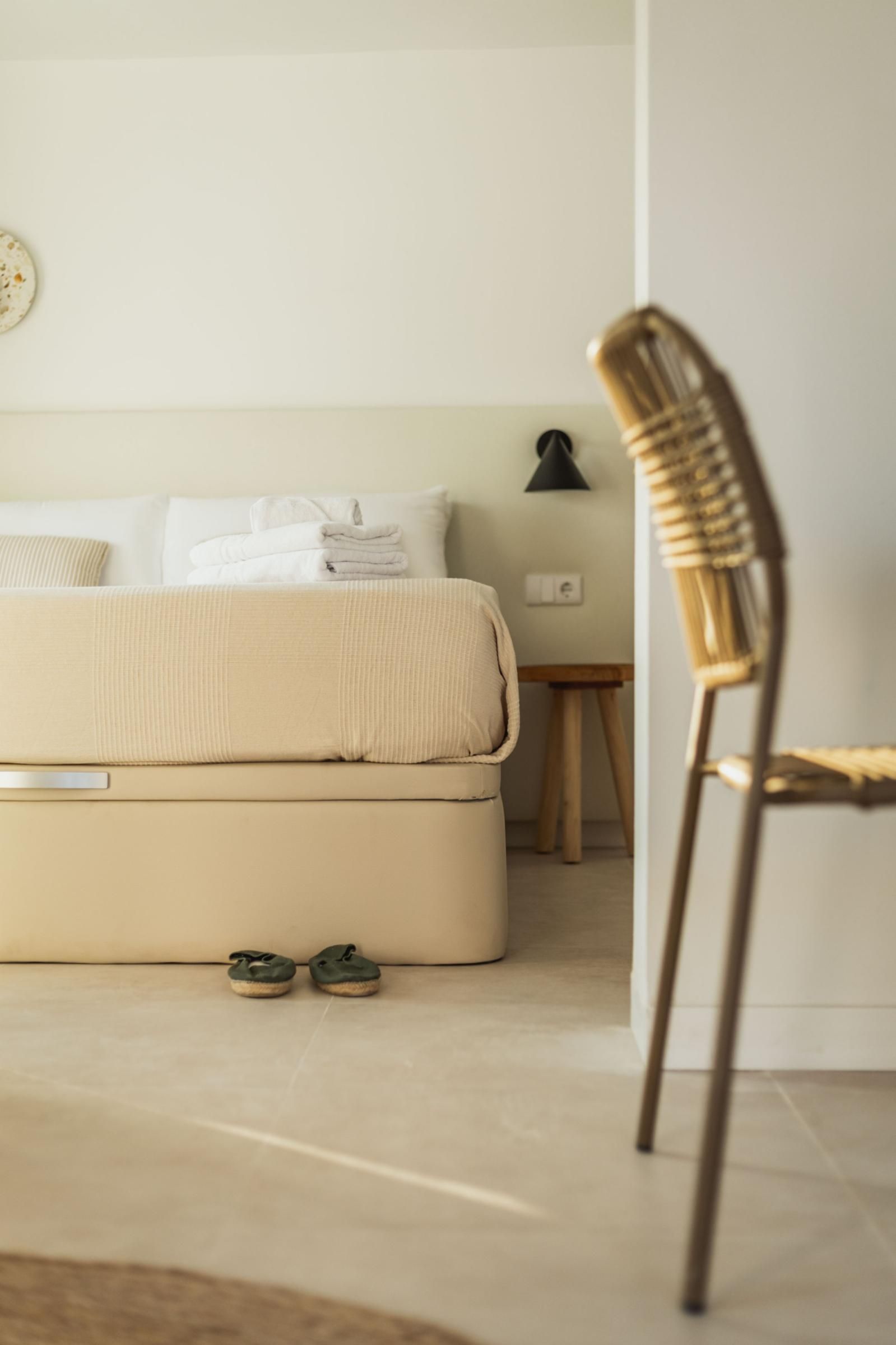 A minimalist bedroom with a bed, a chair, and a nightstand.