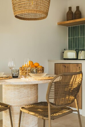 Uma área de refeições com mesa de vime, cadeiras e luminária pendente.
