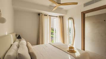 Een slaapkamer met een bed, een plafondventilator, een raam met gordijnen en uitzicht op groen buiten.