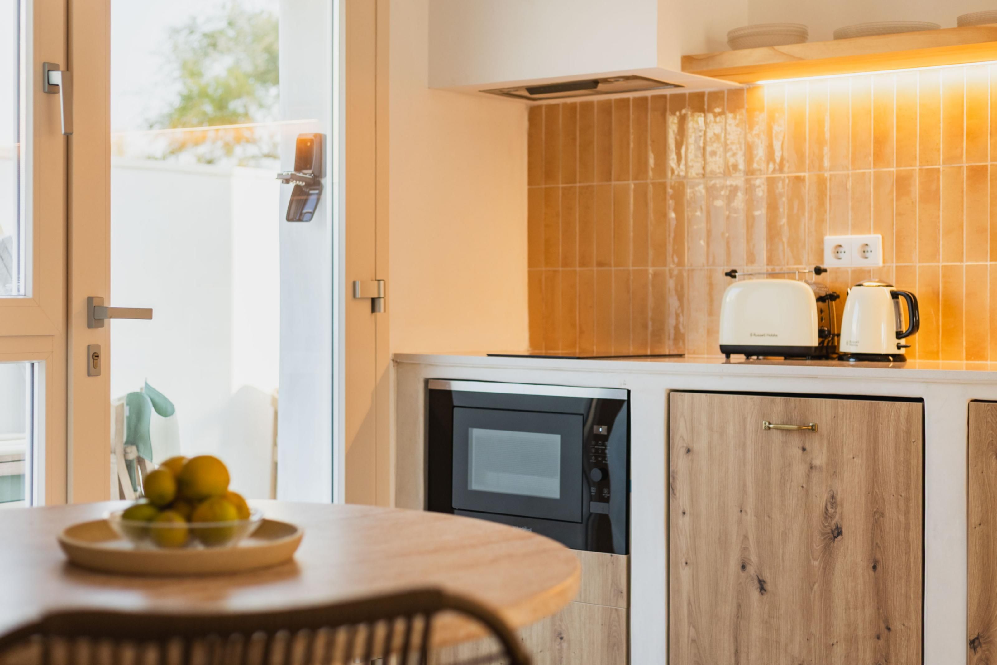 A modern kitchen with a dishwasher, a coffee maker, and a bowl of fruit on the counter.