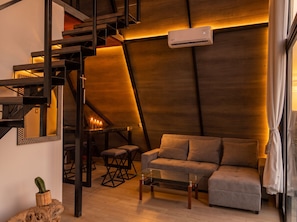 A modern interior with a staircase, a sofa, a glass coffee table, and a cactus plant.