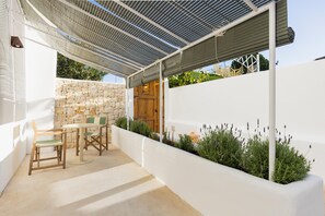 Um pátio externo com parede de pedra, porta de madeira e mesa com cadeiras.