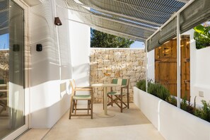 Uma área de pátio com muro de pedra, porta de madeira e mesa com cadeiras.